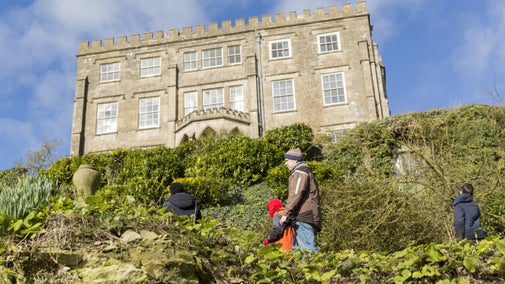 An adult and children outside the south front of Newark Park, Gloucestershire